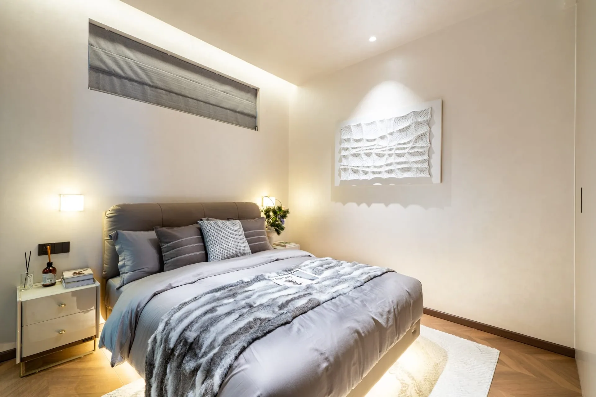 Bedroom in the AYANA Heights show residence with a grey bed and built-in storage